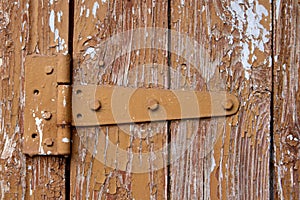 Old rusty hinges on brown wooden cracked door close up