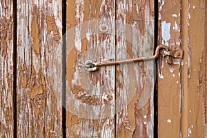 Old rusty hinges on brown wooden cracked door close up