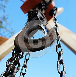 Old rusty hook on blue sky background. Construction industry.
