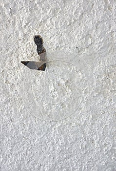 Old rusty hook on a rough white wall