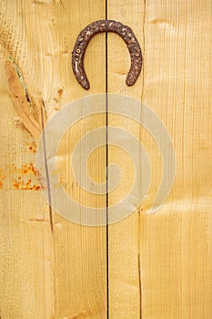 Old rusty horse shoe hanging on a wooden door for good luck. Concept superstition