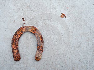 Old rusty horse shoe on a light color surface. Symbol on luck in a country setting. Rural theme