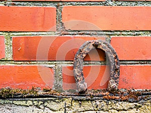 Old rusty horse shoe on a red color brick wall. Symbol on luck in a country setting. Rural theme