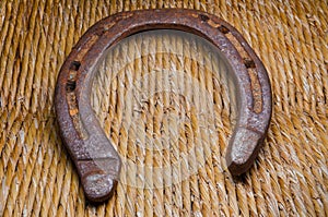 Old rusty horseshoe on caned straw