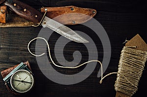 Old rusty hunting bushcraft knife, military compass and a linen rope on the wooden table. photo
