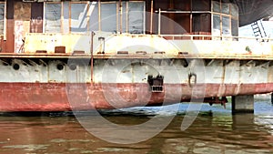 An old rusty inactive ship stands on the dock and the reflection of water