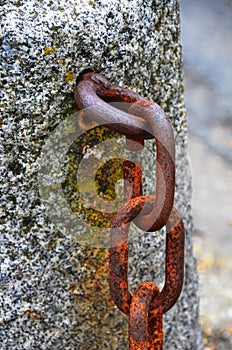 Old rusty iron chain, embedded in granite stone