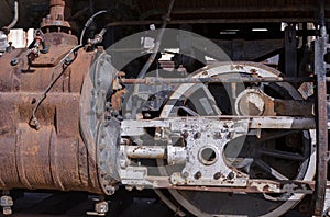 Old rusty iron cylinder and driving rods on a steam engine