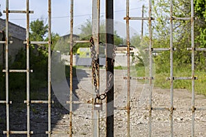 Old rusty iron gate on chain and lock. Closed metal gates. Protection, security and safety concept. padlock on metal gate