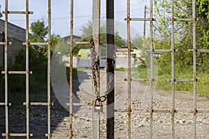 Old rusty iron gate on chain and lock. Closed metal gates. Protection, security and safety concept. padlock on metal gate