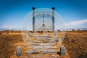 Old rusty iron gate in the middle of a field leading to nowhere. Concept of purgatory, limits, frontiers and freedom