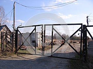 Old rusty iron gates with barbed wire in the abandoned territory of the security company entry is prohibited