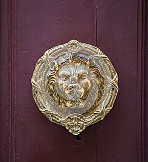 Old golden iron lion head door knocker on a wooden door. Mdina, Malta