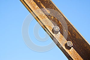 Old rusty iron structure with bolted metal profiles against a blue sky