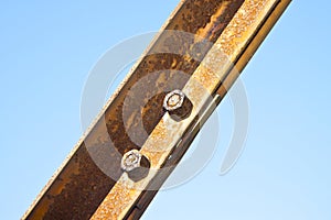 Old rusty iron structure with bolted metal profiles against a blue sky