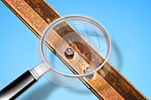 Old rusty iron structure with bolted metal profiles against a blue sky - Concept image seen through a magnifying glass