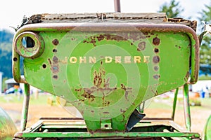 Old, rusty John Deere tractor seat, showing the word mark logo on the back, worn out. Classic John Deere image of an antiquated