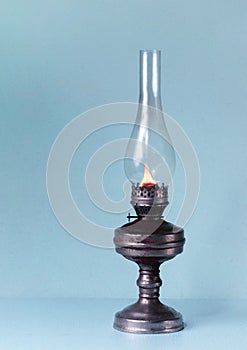 Old rusty kerosene lamp with a lit wick. Retro style