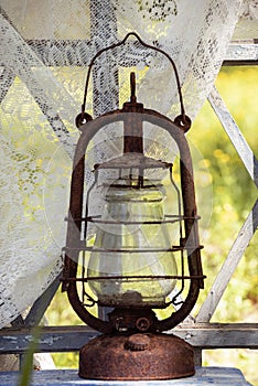 An old rusty kerosene lamp on an old wooden window
