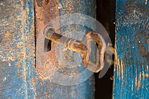 Old rusty key and keyhole on a blue wooden door