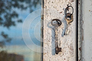 Old rusty key on the shabby wooden door frame with broken white paint