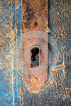 Old rusty keyhole iron plate on beautiful cracked wooden door