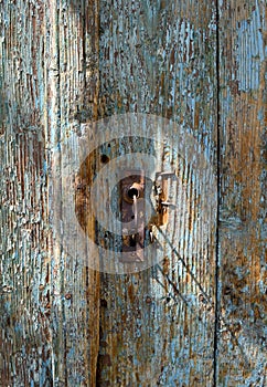 Old rusty keyhole in a weathered old wooden blue door