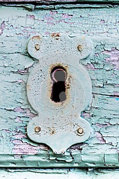 Old rusty keyhole on a wooden door with cracked paint