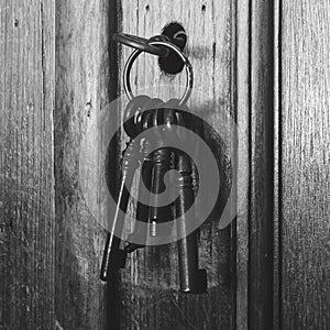 Old rusty keys inside a keyhole of an old antique closet. vintage design black and white