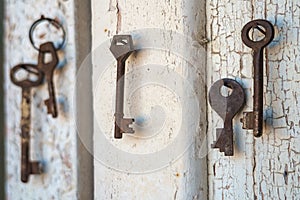 Old rusty keys on the shabby wooden door frame with broken white paint