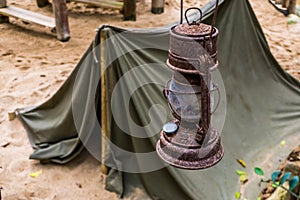 Old rusty lantern with a tent in the background, the Miners camp, survival hike in nature