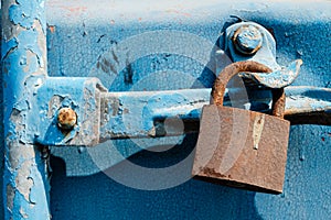 Old rusty lock on a blue background hanging on a sea shipping container