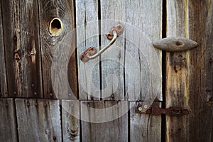 Old rusty lock hanging on the gray wooden door.