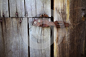 Old rusty lock hanging on the gray wooden door.