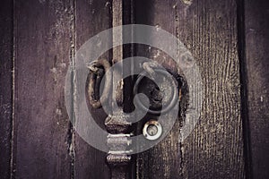 Old rusty lock hook and modern door lock on wooden door.