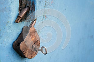 Old rusty lock with a key on a blue background