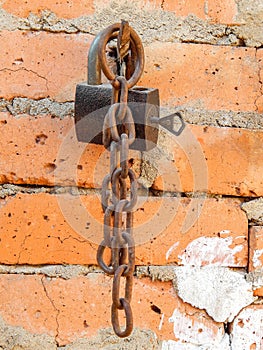 Old rusty lock nailed to a wall with a chain