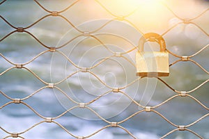 Old rusty lock over iron fence with blue sea background.