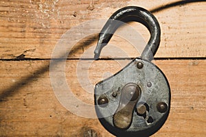 Old rusty lock on a wooden table. Vintage padlock on the wood background