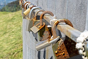 Old rusty love padlocks hanging on railing outdoors