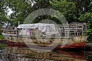 Old rusty machinery boat on the river dock.