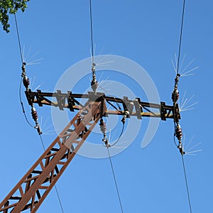 Old rusty mast with a power line above front of blue sky