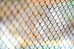 Old rusty mesh fence. Blurred colorful background