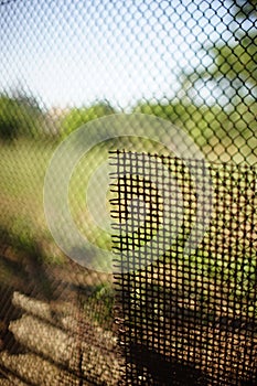 Old rusty mesh fence and the same sheet of rust mesh near the summer garden