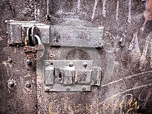 Old grungy metal door with a padlock and latch