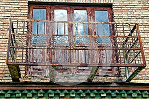 The old rusty metal frame of the balcony on the wall of the house