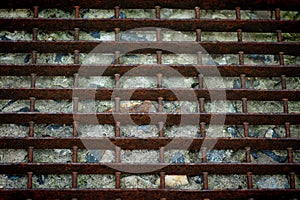 An old, rusty, metal grate lies on the concrete floor