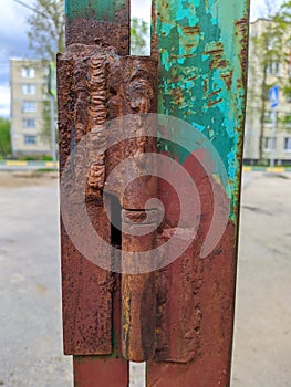 old and rusty metal hinges of an iron fence on a blurred background