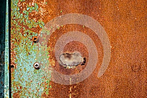 Old rusty metal with hole, painted green which becames orange from rust. Horizontal texture
