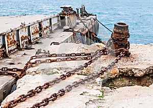 Old, rusty metal mounts and large chains for mooring in the seaport against